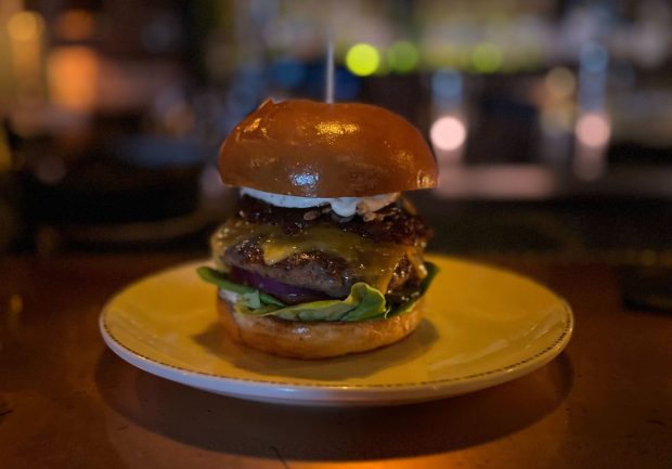 The Wild Style Burger at The Lion's Share is made with a Waygu blend patty, cheddar cheese, lettuce, tomato, onion, pickles, boar bacon jam, crispy shallots and barbecue sauce. (Abby Hamblin / The San Diego Union-Tribune)