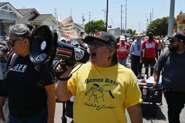 Erendria Ramirez, from Union del Barrio, an pro-migrant activist group, leads a gathering of people marching for a May Day rally in Chicano Park's Barrio Logan neighborhood in San Diego on Friday. (Carlos Moreno / The San Diego Union-Tribune)