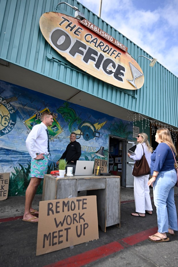 Scott Muirhead, left, talks to people arriving for his remote work event held at The Cardiff Office bar April 24, 2026 in Encinitas, Calif. (Photo by Denis Poroy)