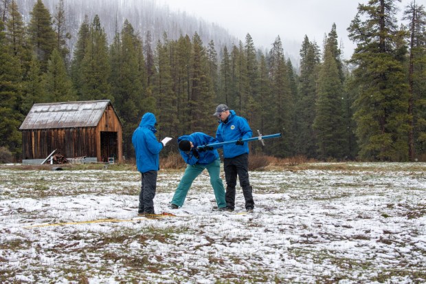 Managers and engineers from the California Department of Water Resources collect meager amounts of snowpack from the Phillips Station in the Sierra Nevada in Eldorado County on April 1, 2026. (Melissa Sanchez Robinson / California Department of Water Resources)