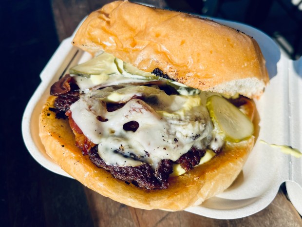 The dry-aged burger from The Wise Ox contains bacon, Havarti, house pickles, mayo and mustard. (Carlos Rico / The San Diego Union-Tribune)