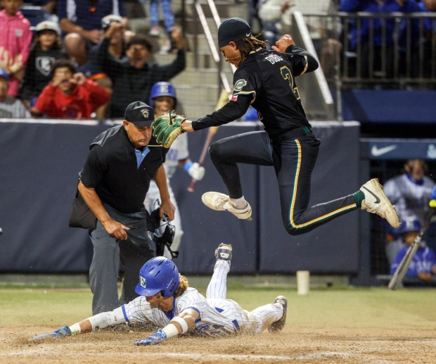 Patrick Henry's pitcher Tyson Bobo jumps over Eastlake's Hamza Hatahet as Hatahet slides into home to score in the sixth inning of the CIF Open Division championship game at USD's Fowler Park in San Diego on Saturday, May 30, 2026. (Hayne Palmour IV / For The San Diego Union-Tribune)