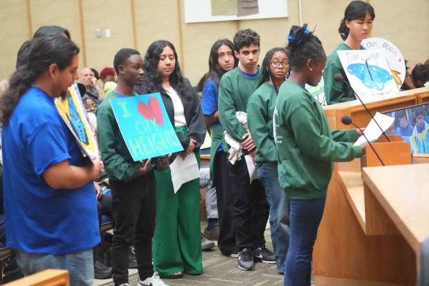 Members of Mid-City CAN hold placards when they speak during the city budget cut hearing at City Hall on Wednesday, May 27, 2026 in San Diego. (Michael Ho / For The San Diego Union-Tribune)