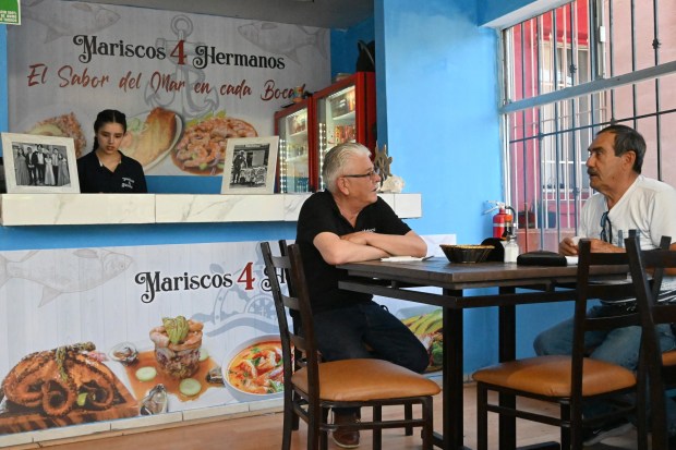 Francisco Duarte speaks to Jose de Jesus Topete (left) who originally is from Jalisco, Mexico and lives in San Diego, as he came to try the new seafood place that Duarte recently opened, a Sonora Mexican style seafood restaurant called "Mariscos 4 Hermanos" (Seafood 4 Siblings) out of curiosity after watching a TV news story about Duarte in Tijuana, Mexico on Friday, May 8, 2026. Duarte lived in National City, California for more than 30 years and worked as a paletero or ice cream street vendor, until October of last year when he was deported from the U.S. back to Mexico. (Carlos Moreno / The San Diego Union-Tribune)