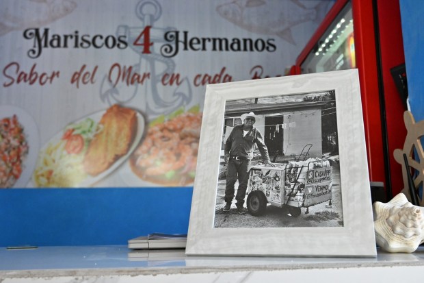 A framed photo of Francisco Duarte as a paletero or ice cream street vendor in National City, California, where he lived and worked for more than 30 years, sits in front of his recently opened Sonora Mexican style seafood restaurant called "Mariscos 4 Hermanos" (Seafood 4 Siblings)'s main counter on Friday, May 8, 2026 in Tijuana, Mexico. (Carlos Moreno / The San Diego Union-Tribune)