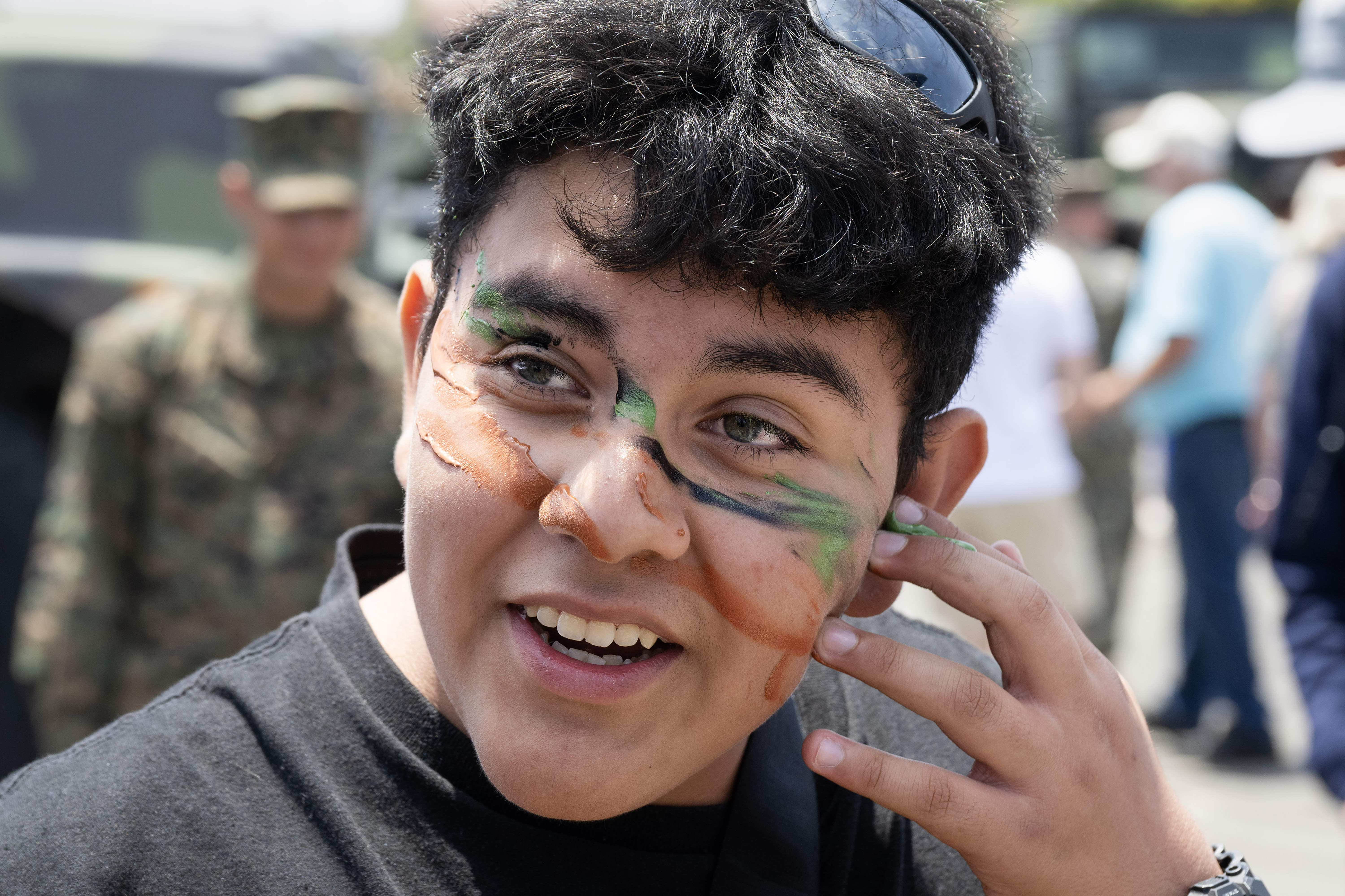 Nicolas Pena applies camouflage face paint during day one of...