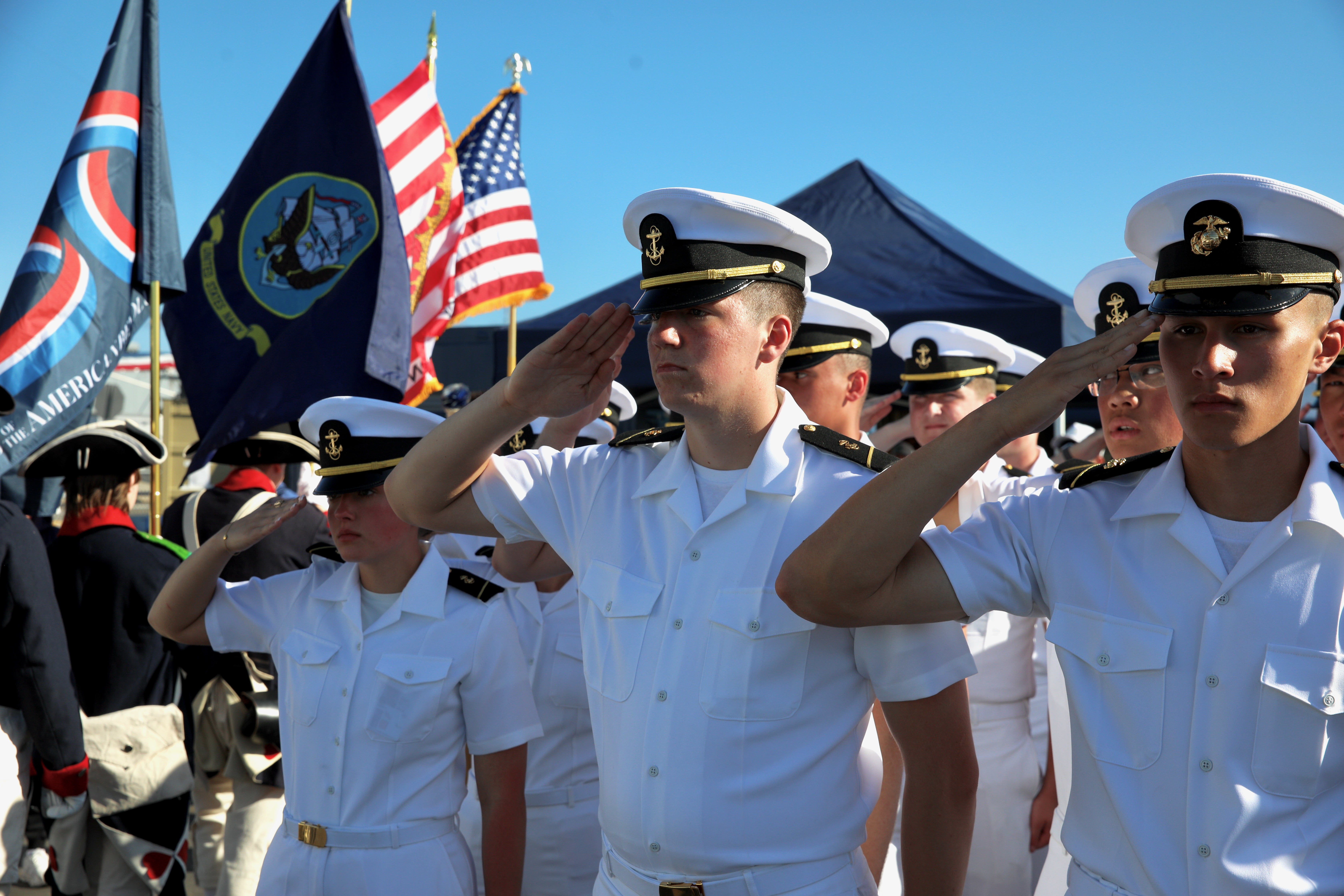 Sailors salute as the Colors are retired at a Memorial...