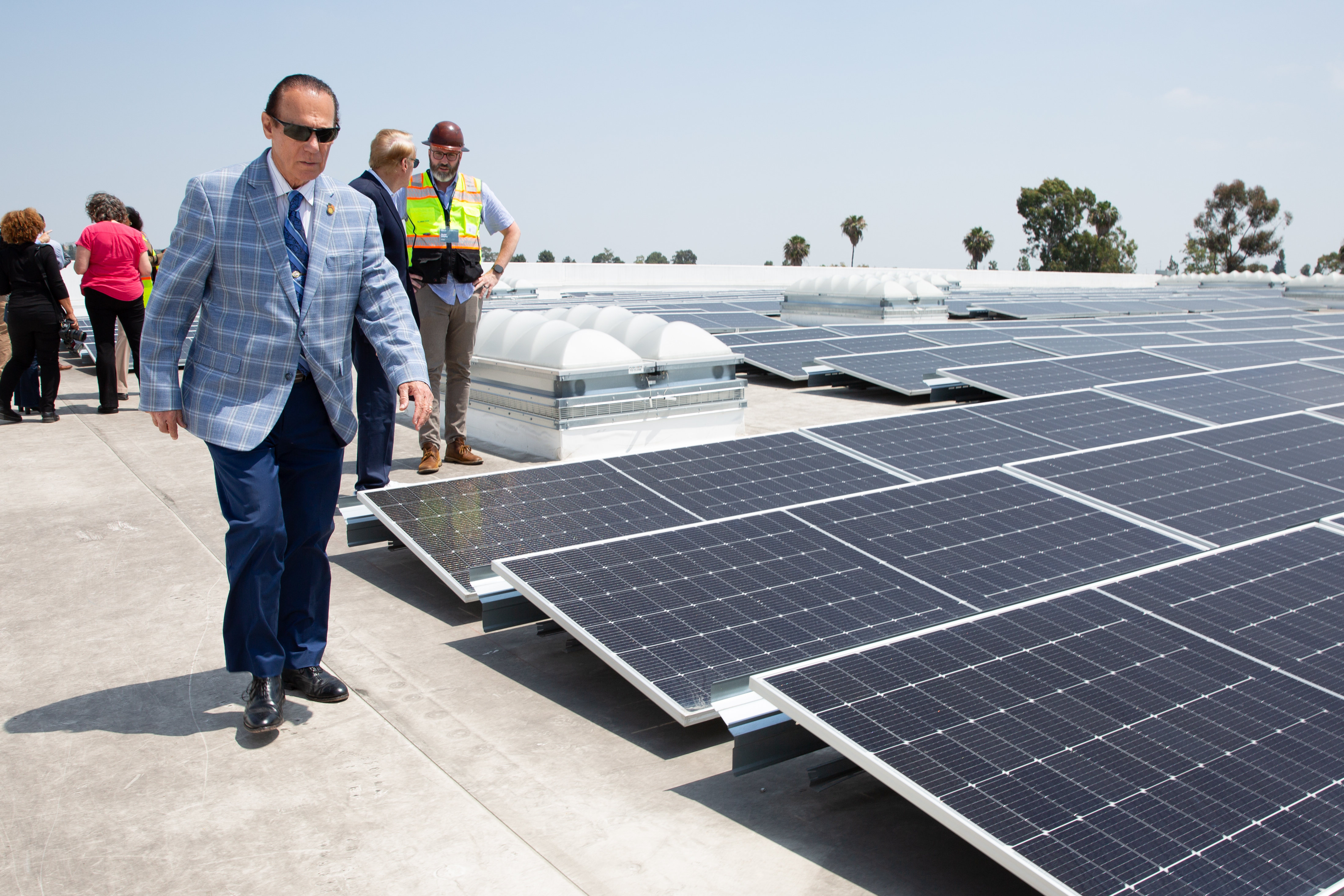 City council member Jim Dear walks past rows of solar...