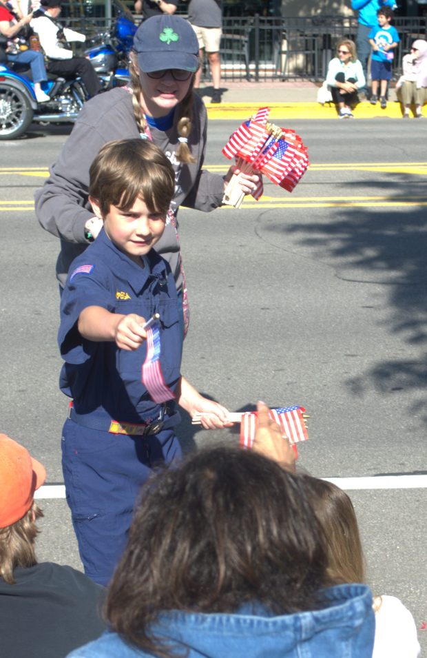 An unidentified Boy Scout hands out flags on Main Street in downtown Royal Oak Monday morning. (JEFF PAYNE--For MediaNews Group)