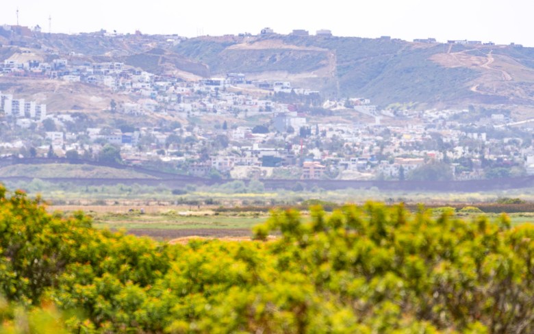 From a verdant green area, there is a view of a ridge filled with housing and other structures.