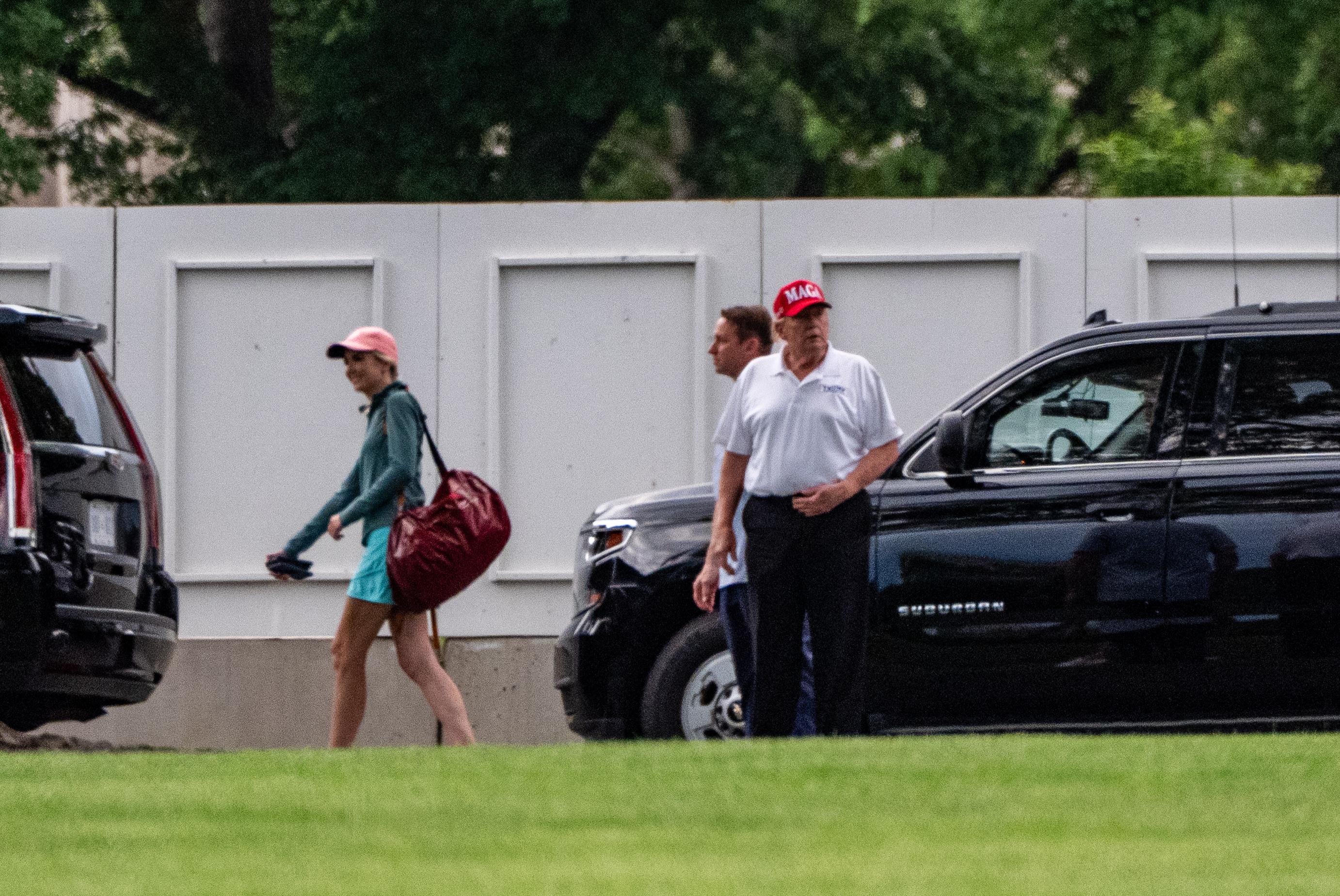 President Donald Trump with White House aide Natalie Harp walks to the White House.
