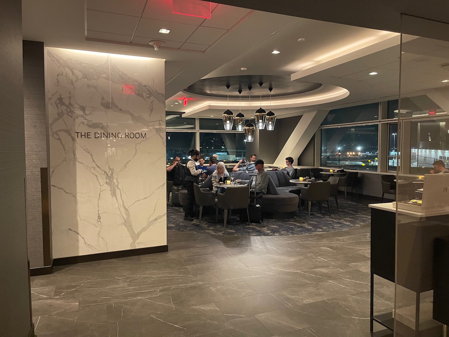 a group of people sitting at tables in a room with a marble wall