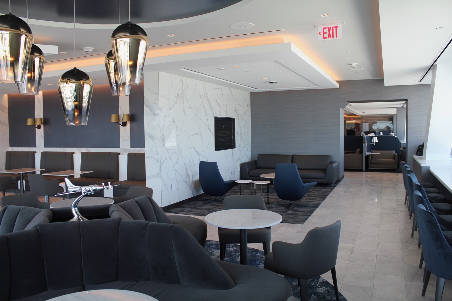 a room with a marble wall and chairs and tables
