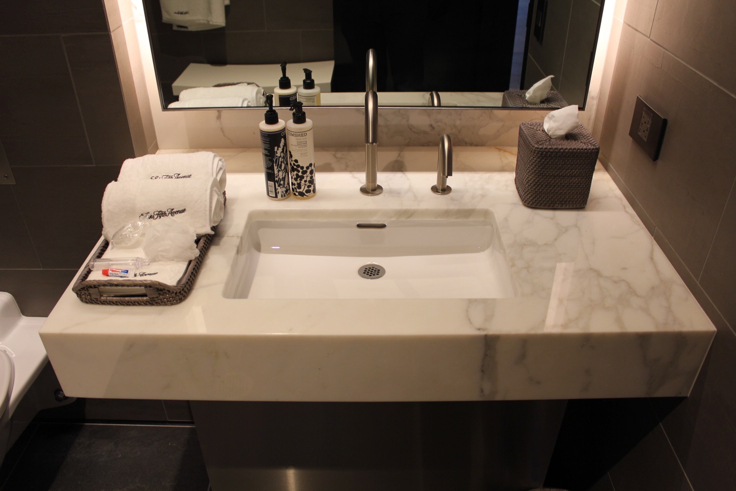 a sink with a mirror and a basket of soaps