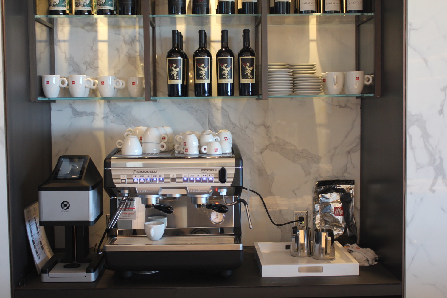 a coffee machine with white cups and saucers on top