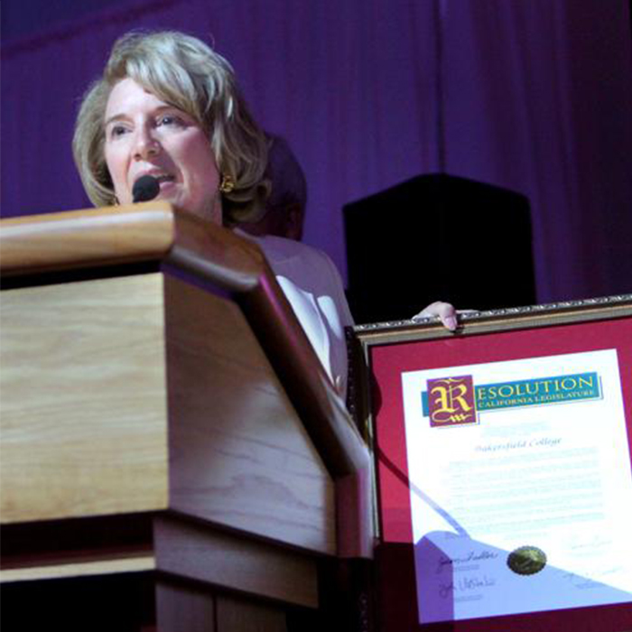 Jean Fuller standing at a podium talking to guests