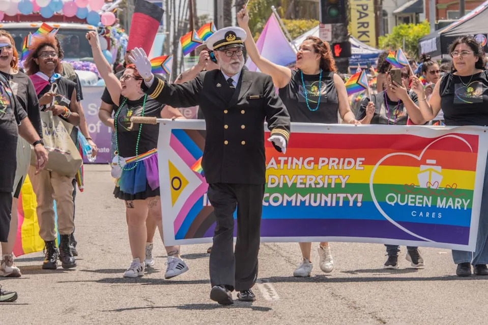 People in a Long Beach Pride Parade holding a banner that reads “Celebrating Pride Diversity Community!” and “Queen Mary Cares” Alberto Sibaja/Pacific Press/Shutterstock
