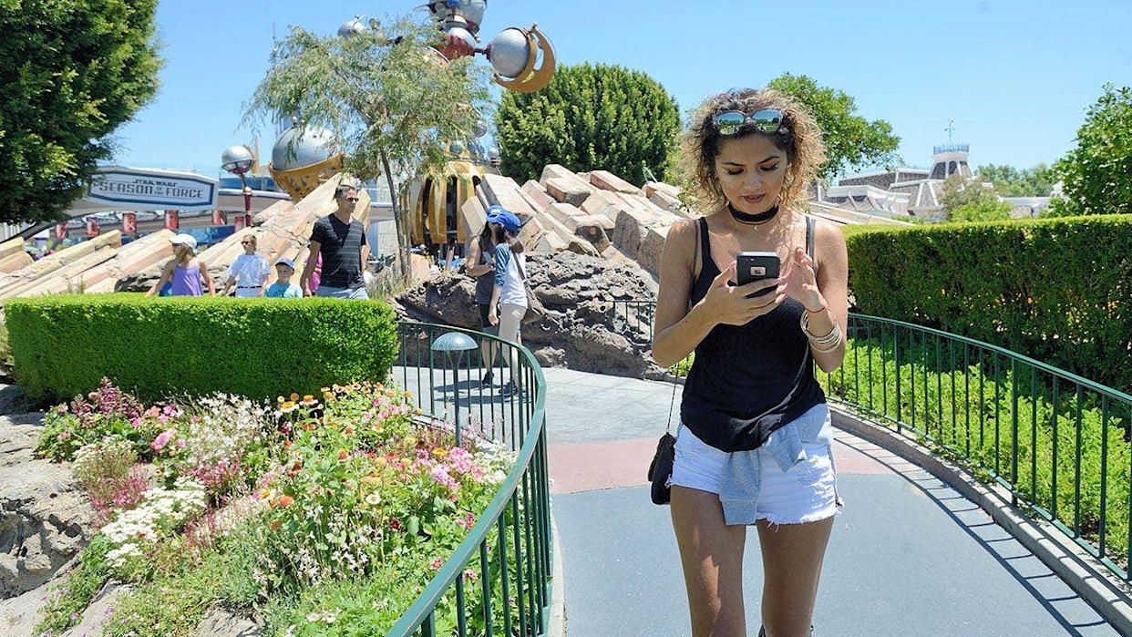 Michelle Mendez walking out of Tomorrowland playing Pokemon Go at Disneyland