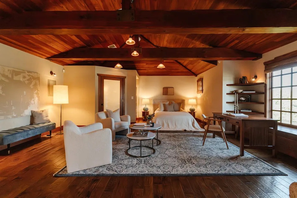 A spacious master suite with a dramatic vaulted wood-plank ceiling, exposed beams, and dark hardwood floors.