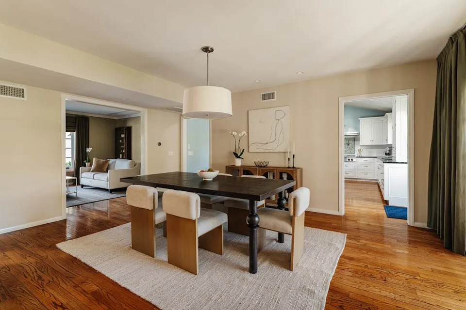 A formal dining room with a dark wood table, unique block-style chairs, and a large drum pendant light.