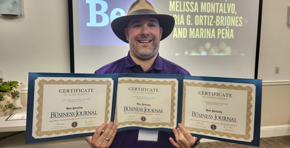 man in cool hat holds three certificates