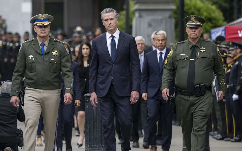 Gov. Gavin Newsom is escorted by California Highway Patrol Commissioner Sean Duryee, left, and California Peace Officers’ Memorial Foundation President Juan Viramontes during the 48th annual California Peace Officers’ Memorial enrollment ceremony in Sacramento on Monday.
