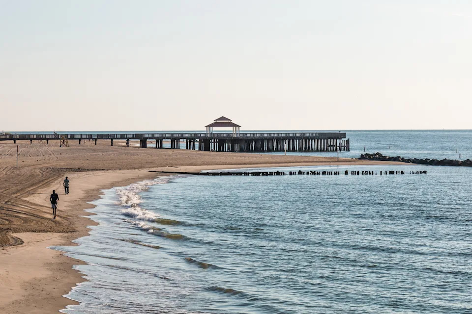 People on Buckroe Beach in the early morning near the pier with gazebo.