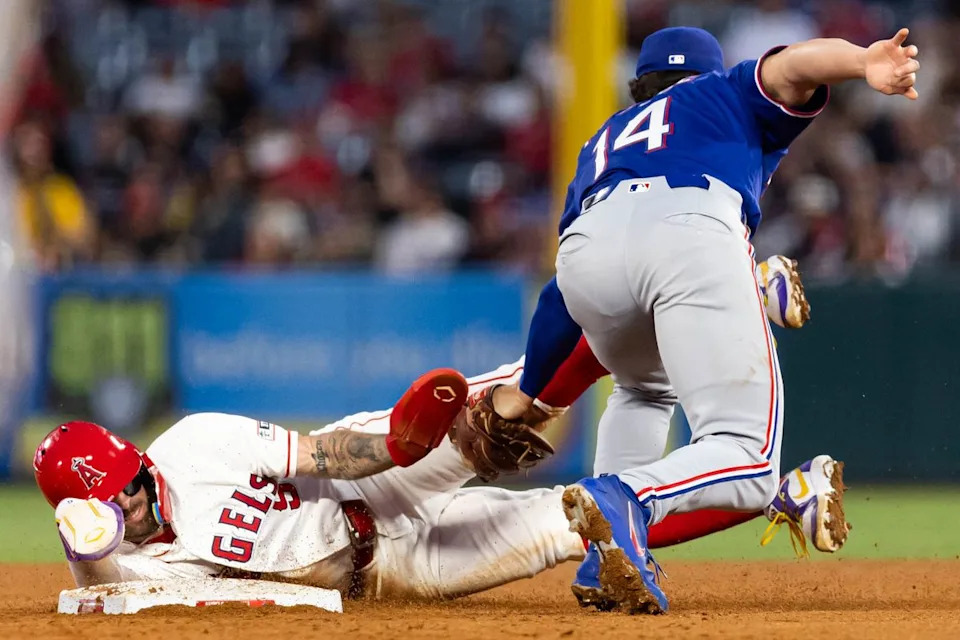 Zach Neto #9 of the Los Angeles Angels is caught stealing by Justin Foscue #14 of the Texas Rangers during an MLB game against the Texas Rangers on May 23, 2026 at Angel Stadium in Anaheim, California.