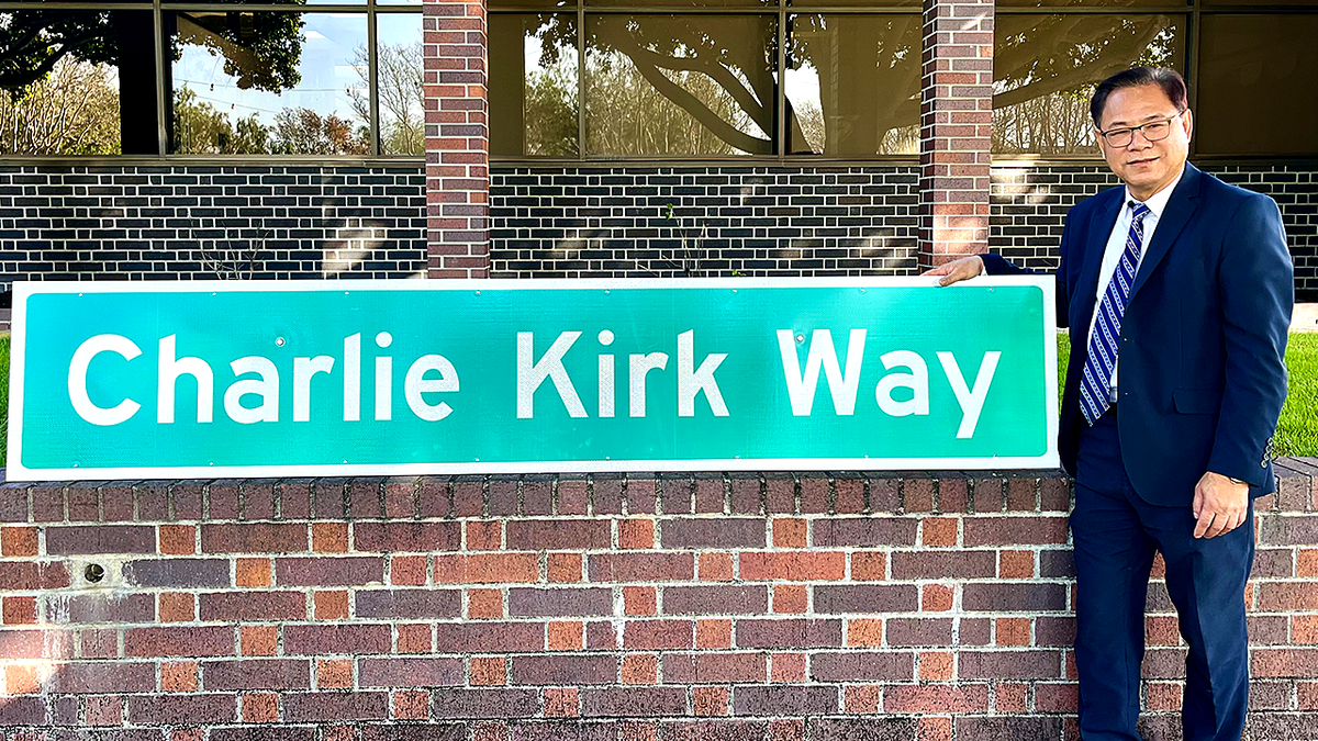 Westminster Mayor Chi Charlie Nguyen standing next to Charlie Kirk Way sign