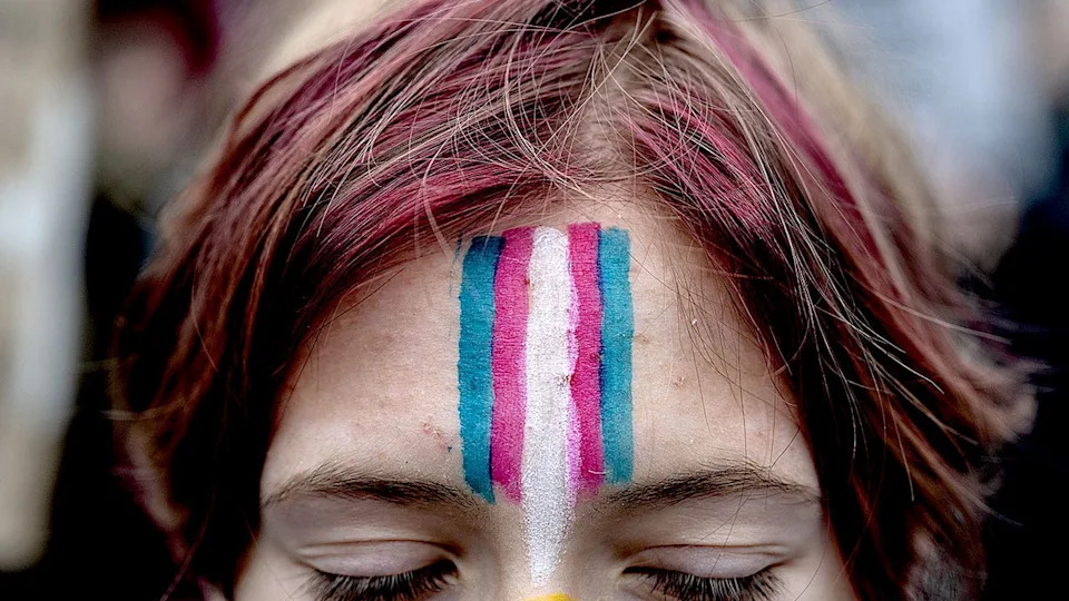 Demonstrator with transgender flag face paint at rally in New York