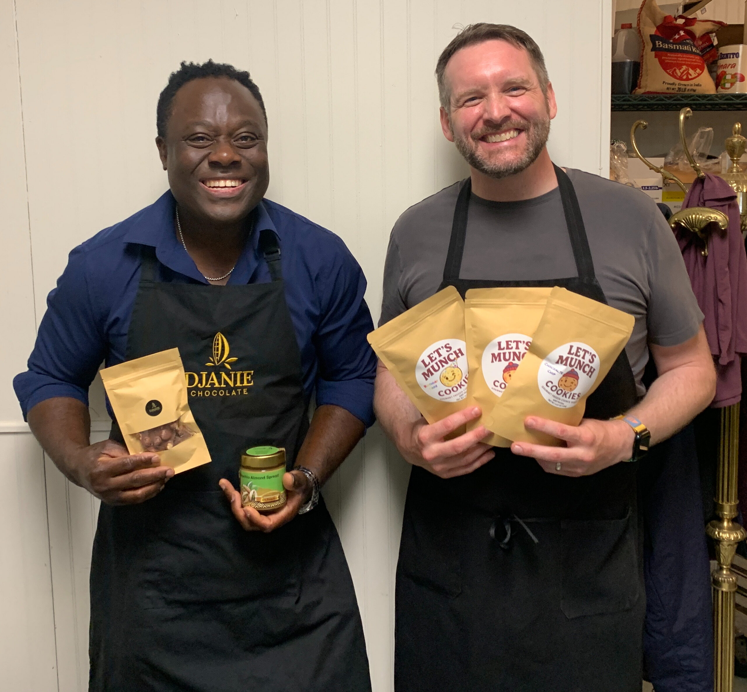 two men standing side by side holding food products