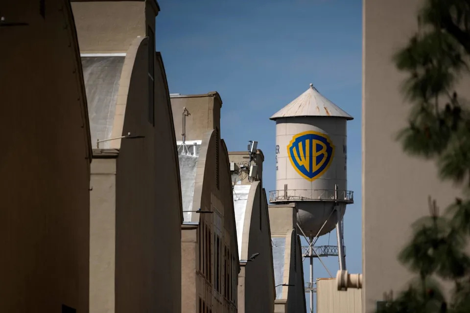 A water tower with the letters "WB" stands beyond a row of buildings.