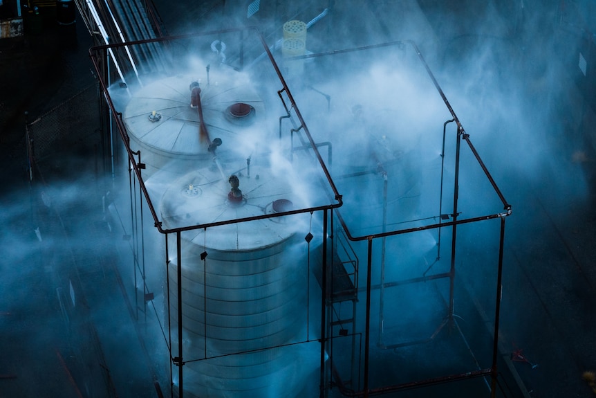 A silver tank with smoke pluming out of it