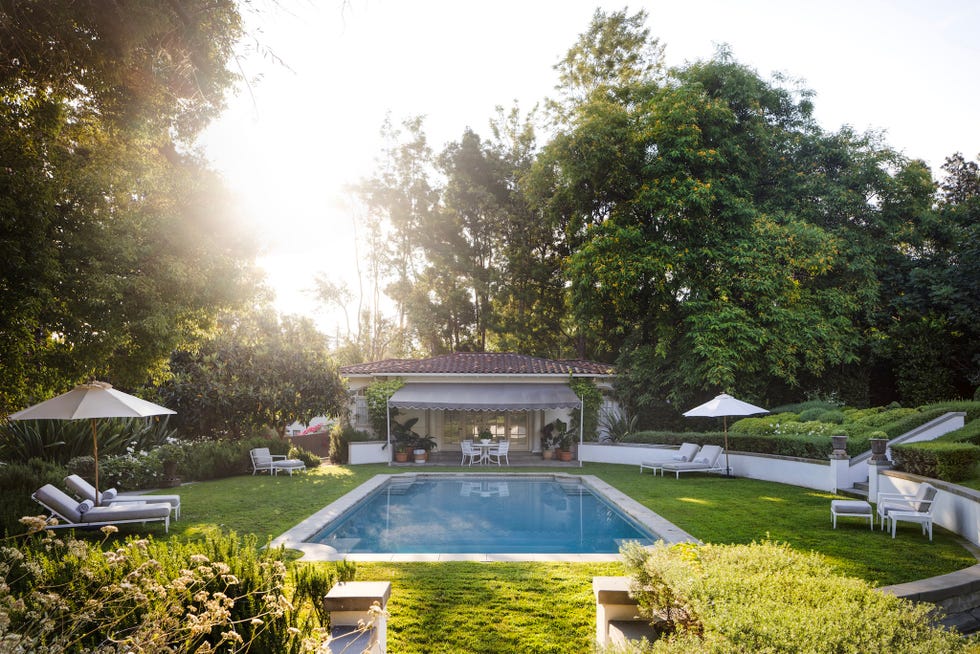 Backyard with a pool, patio, and lush greenery. Backyard with a pool, patio, and lush greenery.