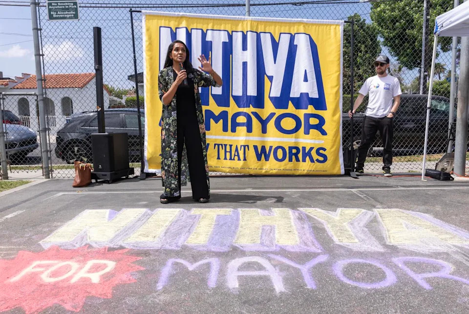 Nithya Raman speaks in front of a Nithya for Mayor banner and chalk writing on pavement
