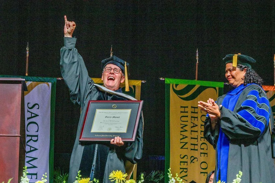 Garry Maisel, CEO emeritus of Western Health, makes the “stingers up” gesture after receiving an honorary Doctor of Humane Letters at a Sacramento State commencement ceremony at Golden 1 Center on Friday.