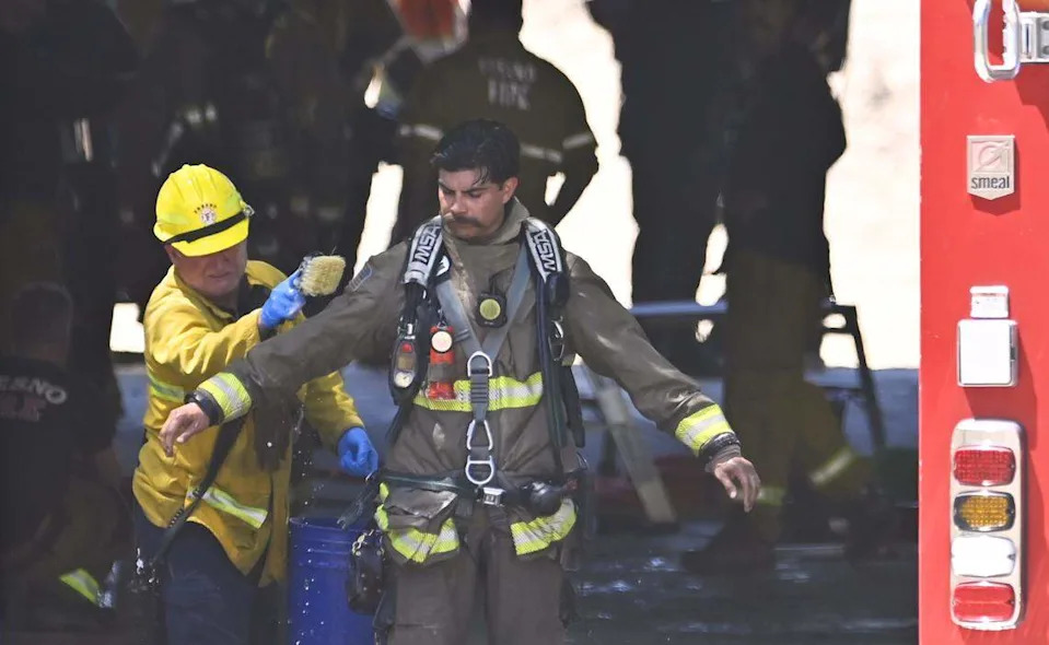 A team member is scrubbed down after emergency teams responded to the discovery of two bodies found in an underground chamber below the H Street overpass along Fresno Street Monday morning, May 11, 2026 in downtown Fresno.