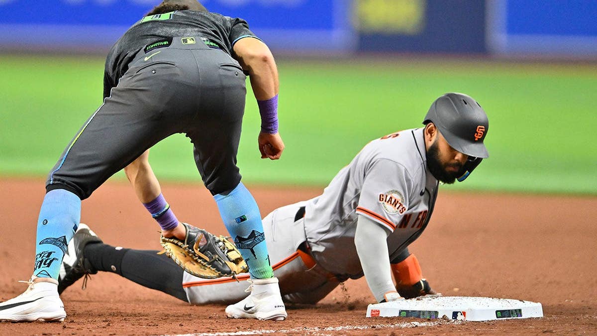 San Francisco Giants Heliot Ramos sliding to first base as Tampa Bay Rays first baseman Jonathan Aranda tags him at Tropicana Field