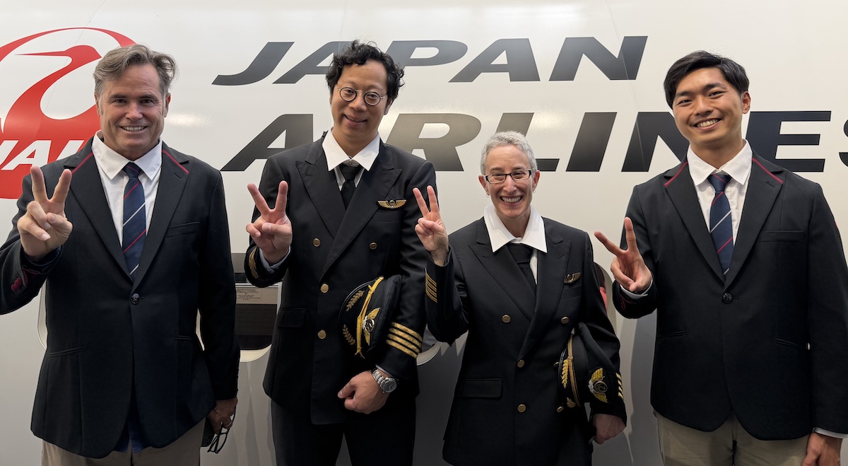 four people standing in front of a plane wearing uniforms
