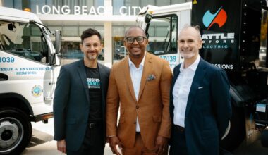 Mayor Rex Richardson and advocates stand alongside two electric garbage trucks.