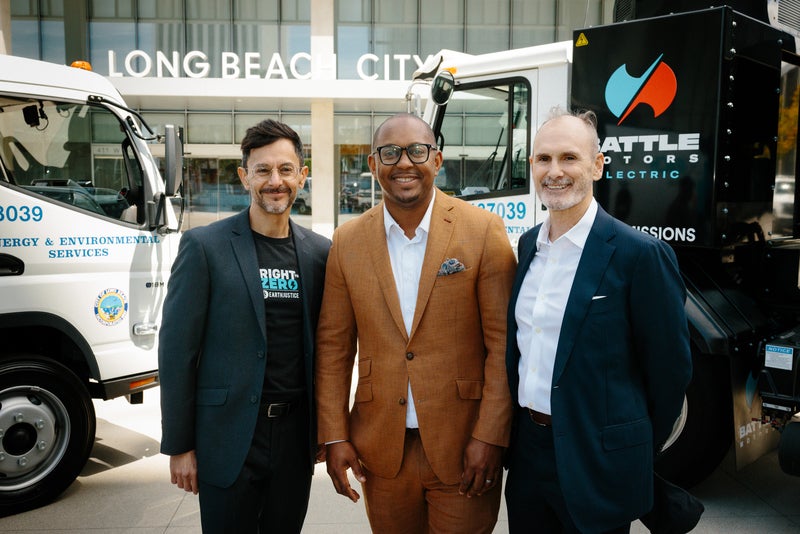 Mayor Rex Richardson and advocates stand alongside two electric garbage trucks.
