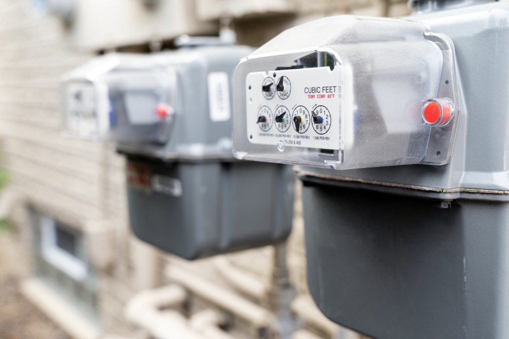Row of gray natural gas meters at an apartment complex.