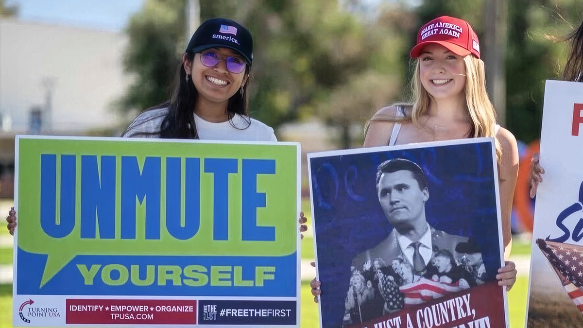 Sadie Burnett holding a Charlie Kirk sign and wearing a MAGA hat
