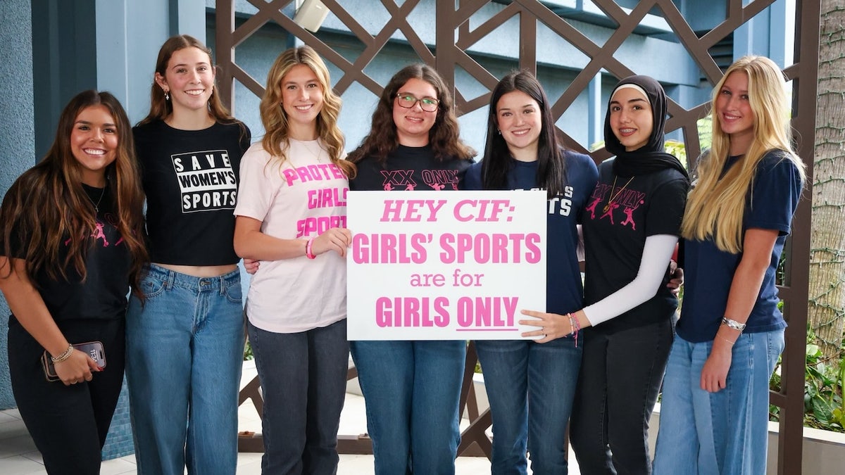 Save Girls Sports activists holding signs at a rally outside a council meeting in Long Beach