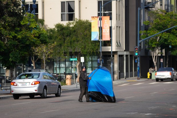 During a recent encampment abatement on F Street downtown, one man dragged his tent to the other side of the street. (Nelvin C. Cepeda / The San Diego Union-Tribune)