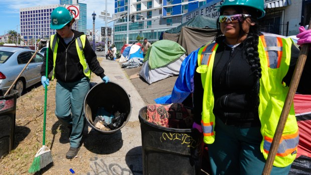 City crews collect trash and debris on National Avenue during an encampment abatement. (Nelvin C. Cepeda / The San Diego Union-Tribune)