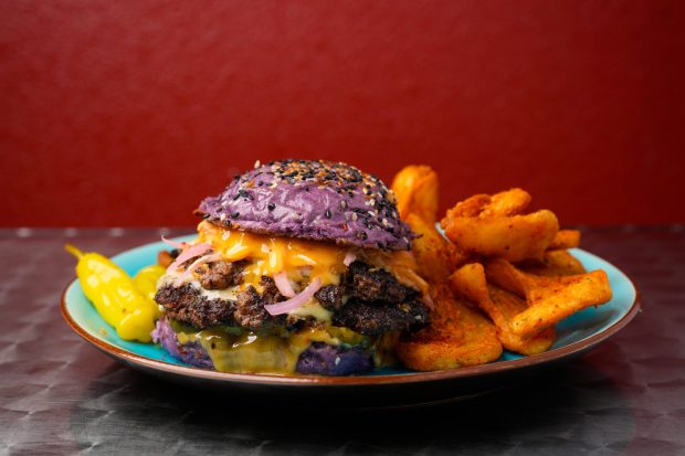 Spring Valley, CA - May 08: A purple bun on a burger might put off some, but they would be missing out on a savory and sweet meal. Tambayan Filipino BBQ & Grill is serving a double American Wagyu smash burger on a sweet and fluffy housemade ube milk bun. The meat is cooked medium and is soft and juicy. The sweet chili aioli sauce gives the burger a slightly tangy heat to it, the pickled red onion and butter pickles offer crunch and texture, and the white American cheese adds gooeyness.  (Nelvin C. Cepeda / The San Diego Union-Tribune)