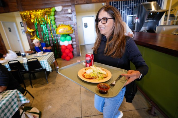 On Tuesday, May 12, 2026, in San Diego, CA, after waiting in line with her husband David Ramirez, Silvia Ramirez of North Park looks for a table during the reopening of Las Cuatros Milpas in Barrio Logan.  (Nelvin C. Cepeda / The San Diego Union-Tribune)
