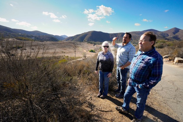 Local residents Debbie O'Neill, left, and her husband Jon Dummer, right, along with J.P. Theberge look over roughly 39 acres of land that a developer wants to build into a residential community in Harmony Grove. The residents oppose the proposed development due to the single two-lane entry and exit road into the community. (Nelvin C. Cepeda / The San Diego Union-Tribune)