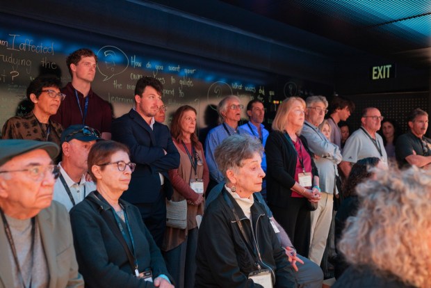 Attendees watch "Holocaust 101," an interactive video shown inside the Spark Interactive bus during its launch event at Crownair Aviation in San Diego on May 3, 2026. (McKenzie Patterson / For The San Diego Union-Tribune)